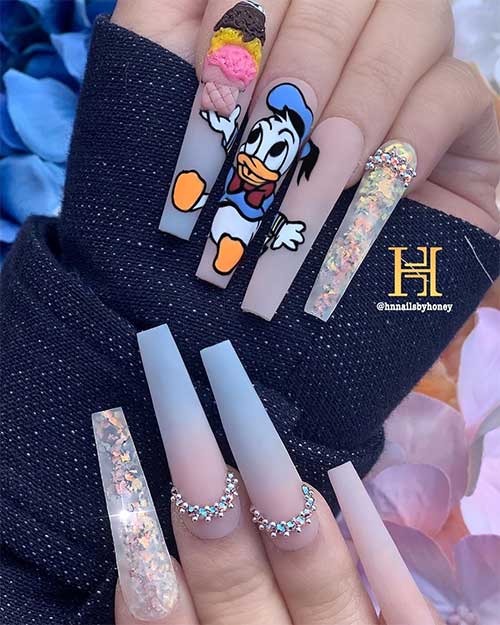 Cute blue ombre matte nails 2020 with hand painted, rhinestones, and encapsulated glitter on accent clear coffin nail design