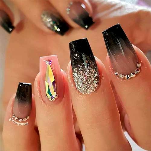 Black coffin ombre nails with gold glitter on accent nail and big rhinestone on nude accent nail design