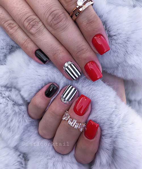 Cute red nails with black accent nail and second accent black and white striped nail with rhinestones