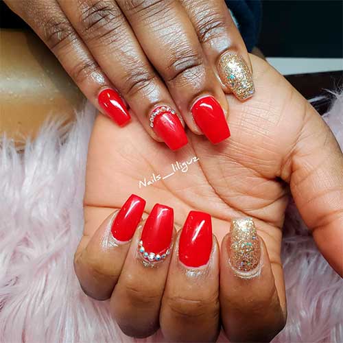 Cute short red coffin nails with rhinestones on accent nail and gold glitter accent nail