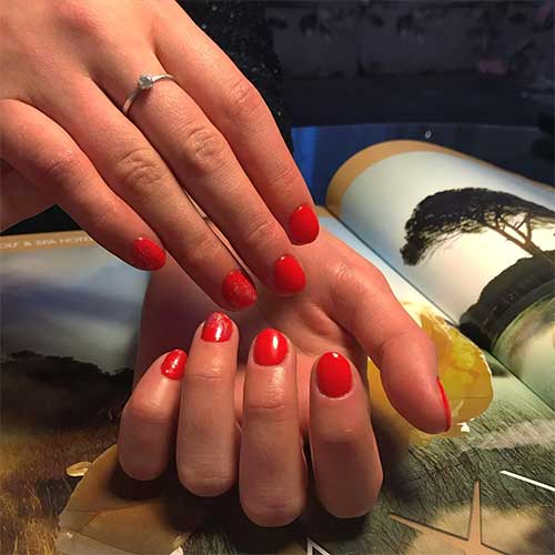 Gorgeous short red round nails with glitter on two accent nails