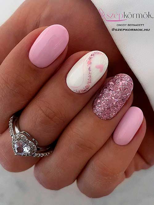 Short pink valentine’s nails with pink glitter and a heart shape on a white accent nail