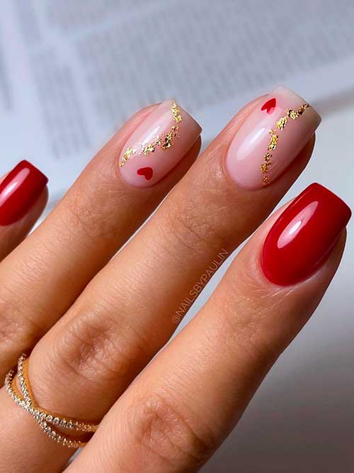 Short red valentine’s nails 2023 with tiny red hearts and gold glitter on two nude pink accent nails