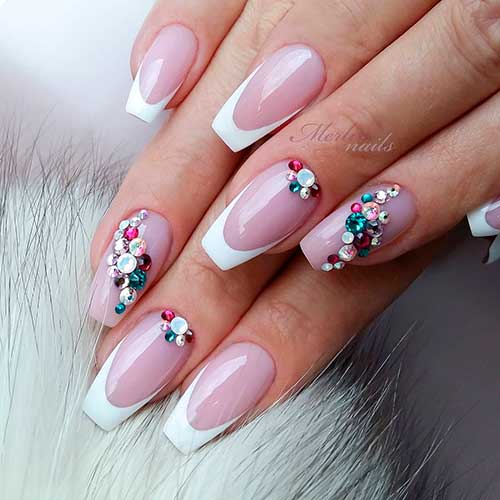 White coffin shaped V French tip nails with colorful rhinestones and nude pink base color! White coffin shaped V French tip nails with colorful rhinestones and nude pink base color!