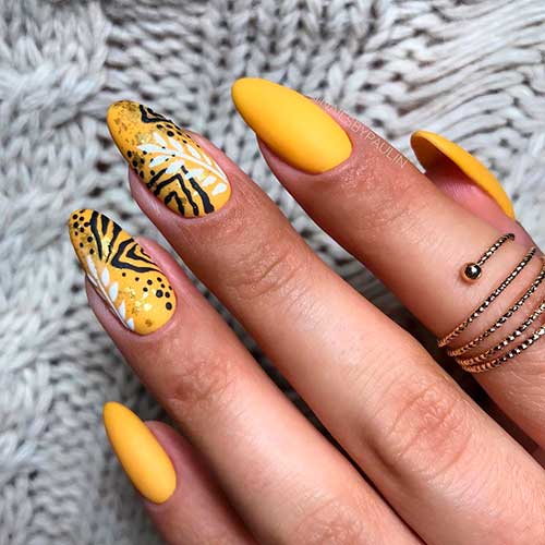 Autumn matte yellow nails 2020 almond shaped with two accent yellow nails adorned with white leaves and black drawing look - yellow nail designs