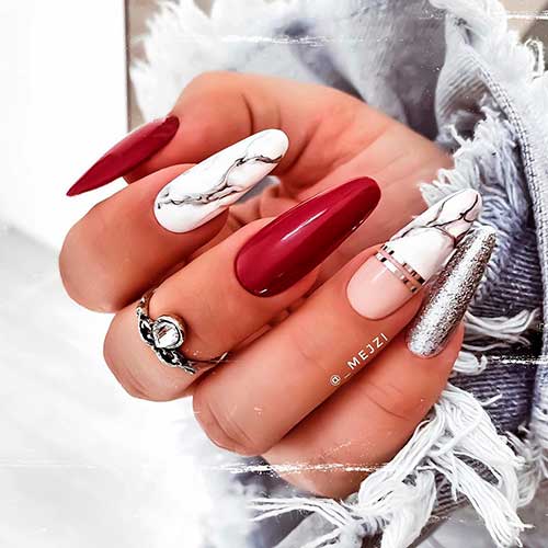 Cute almond shaped white marble nails 2020 with two accent dark red nails and silver glitter accent nail design!