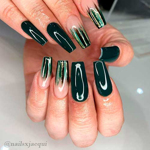 Dark green nails coffin shaped with black, light green, gold glitter, and dark green dashes on two accent tips!