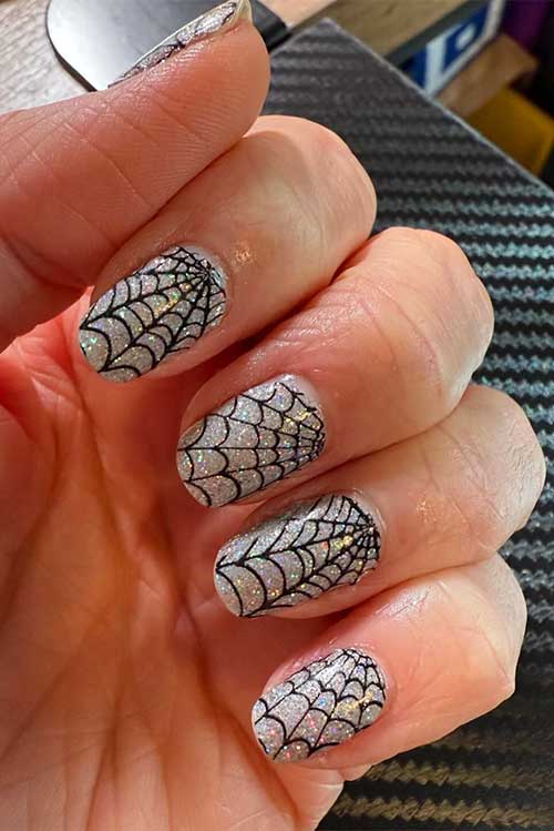 Widow's Glow nail polish strips with holographic glitter and spider web designs, perfect for a captivating nail look. Widow's Glow nail polish strips with holographic glitter and spider web designs, perfect for a captivating nail look.