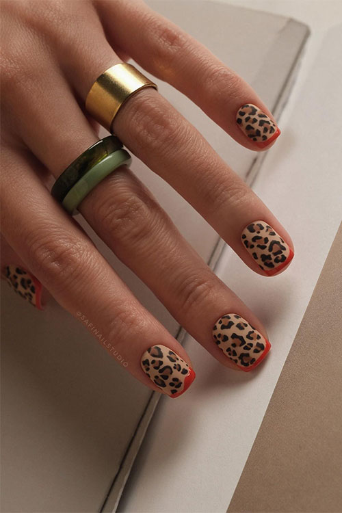 Short brown and black leopard print nails over matte nude base color with minimalist orange French tips Short brown and black leopard print nails over matte nude base color with minimalist orange French tips