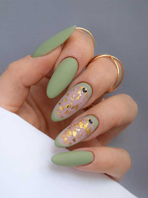 Long almond matte olive green nails 2023 with gold foil and small black heart shapes on two accent nails
