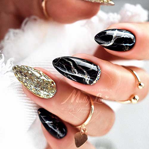 Almond shaped black marble nails with an accent gold glitter nail design