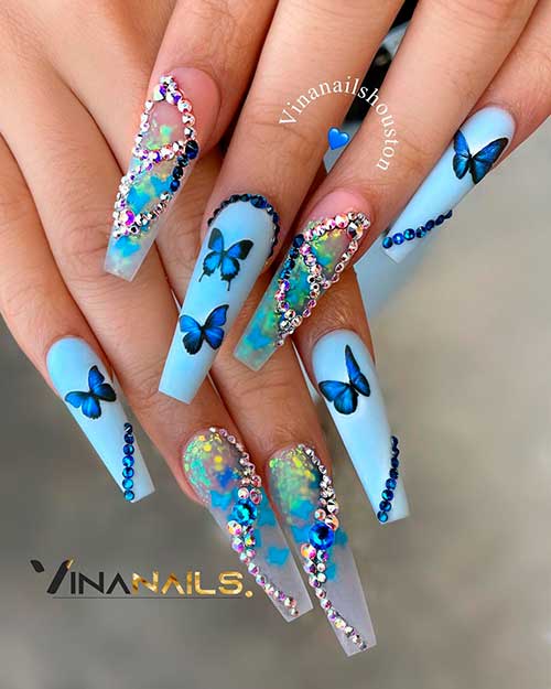 Cute matte light blue nails with dark blue butterfly nail art and two accent clear nails with rhinestones!