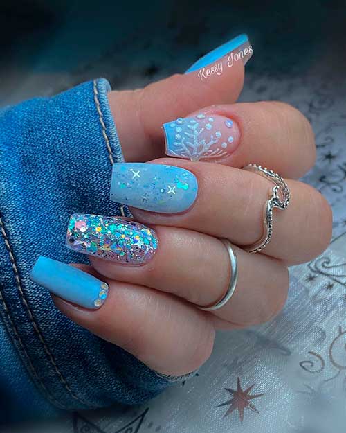 Ice blue coffin winter nails that adorned with silver glitter, white snowflake, and rhinestones.