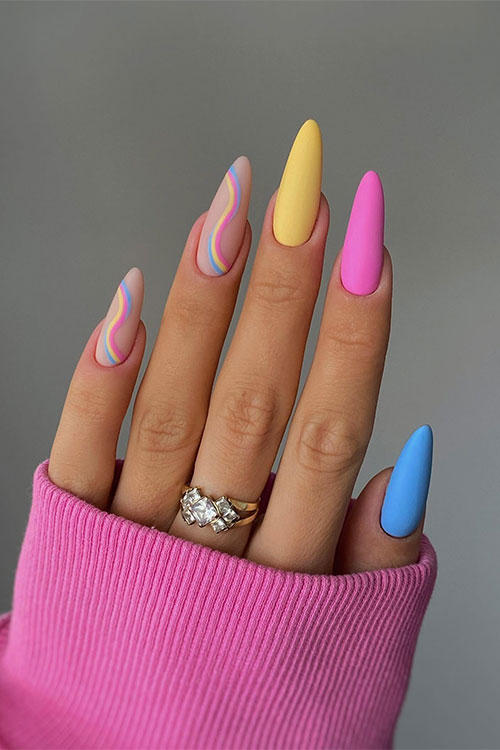 Matte almond-shaped pink blue and yellow nails with two accent nude nails adorned with pink blue and yellow swirls