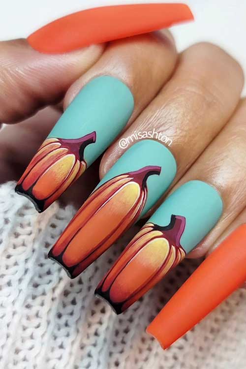 Long matte coffin fall nails consist of burnt orange with hand-painted pumpkins on three light green-blue accent nails Long matte coffin fall nails consist of burnt orange with hand-painted pumpkins on three light green-blue accent nails
