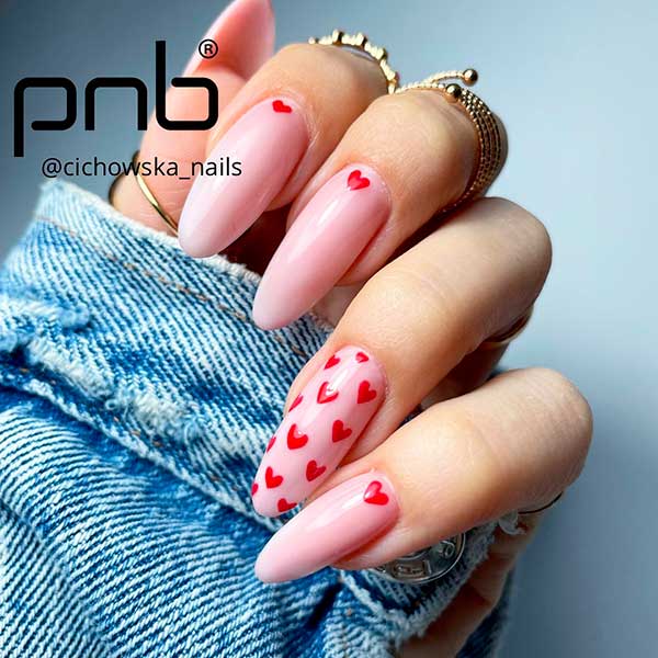 Long nude Valentine’s Day nails 2023 with tiny red hearts to show your love