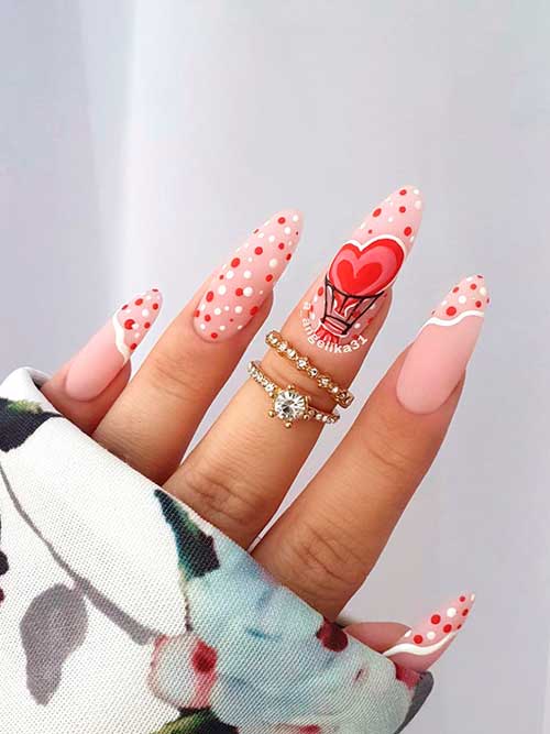 Long matte nude valentine’s nails with red and white polka dot nail art with heart shapes on an accent nail