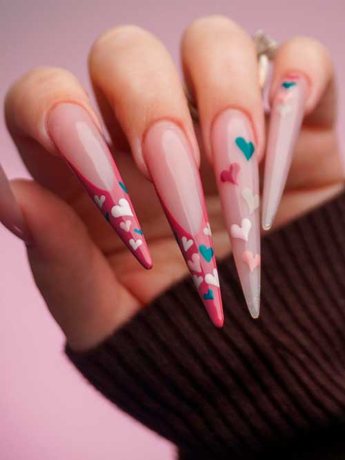Long stiletto nude valentine’s nails with colorful small heart shapes and two red French accent nails