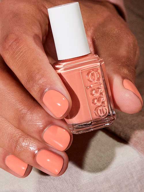 Short pinky coral nails using Essie snooze in nail polish from the unguilty pleasures collection