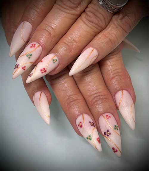 Long almond-shaped shimmer ivory nails with colorful flowers and gold glitter swirl nail art for the spring season