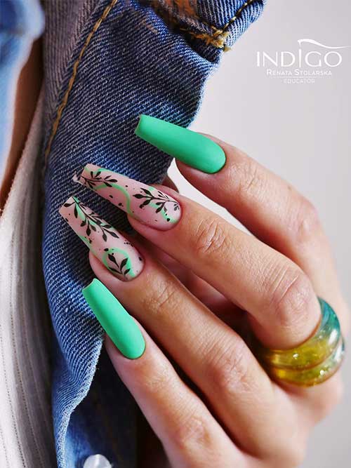Long matte green coffin nails with black leaf nail art and green swirls on two accent nude nails