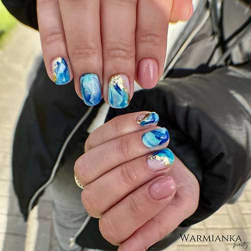 Short blue marble nails with gold foil and nude accent nails for the summer season