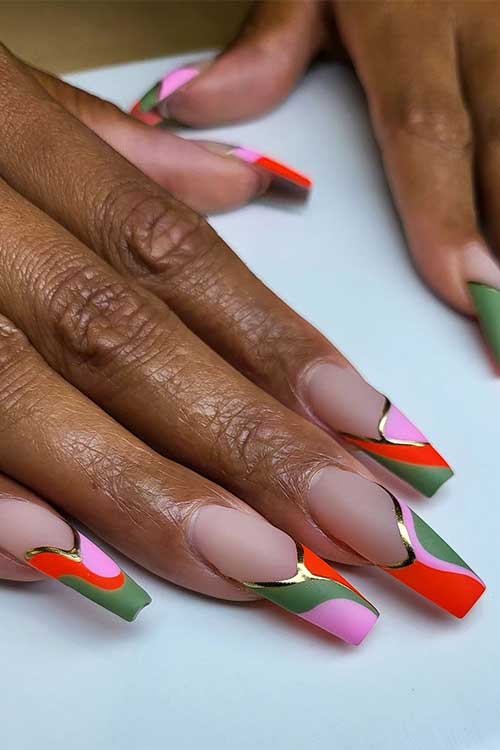 Long coffin French tip nails feature matte pink, green, neon red, and gold metallic swirl nail art Long coffin French tip nails feature matte pink, green, neon red, and gold metallic swirl nail art