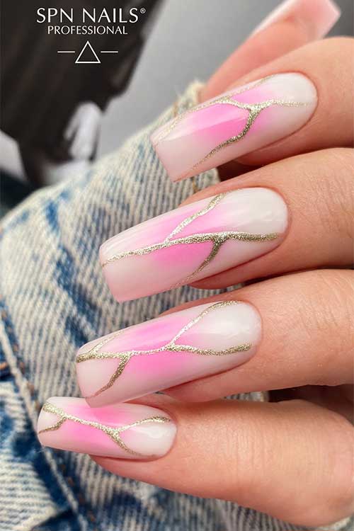 Long milky white nails with gold glitter swirls and a touch of neon pink on the nail center