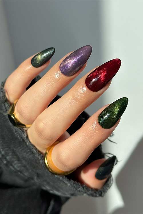 Medium almond shaped magical colorful autumn nails feature dark green, purple, and red colors with glitter