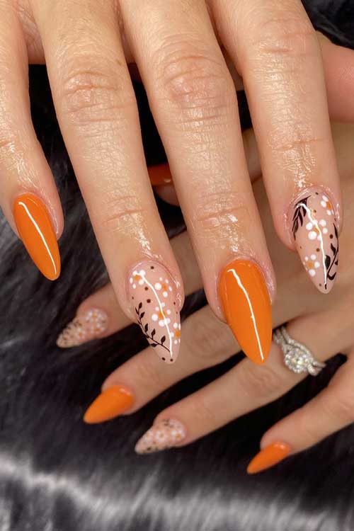 Long almond burnt orange nails with leaf nail art and flowers on two accent nude nails