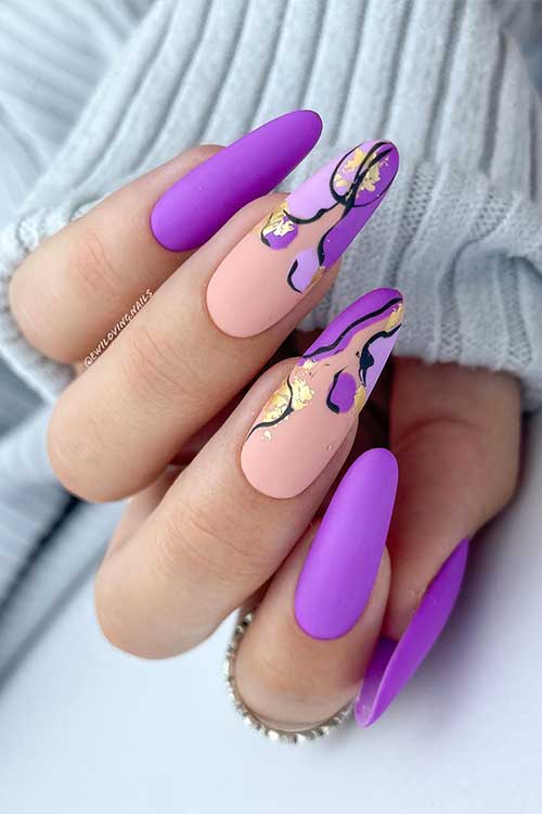 Long matte light purple nails with abstract nail art using black, lilac, and light purple colors and gold foil flakes. Long matte light purple nails with abstract nail art using black, lilac, and light purple colors and gold foil flakes.