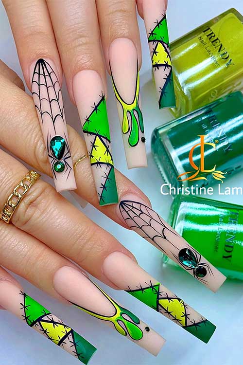 Long nude nails with vibrant green and yellow patches with stitches nail art, drip nail art, cobwebs, and spiders