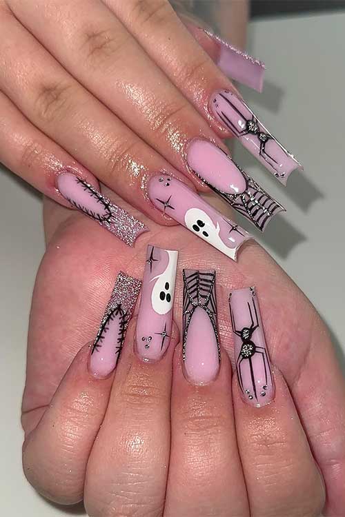 Long nude pink Halloween nails with spiders, cobwebs, and ghosts adorned with silver glitter