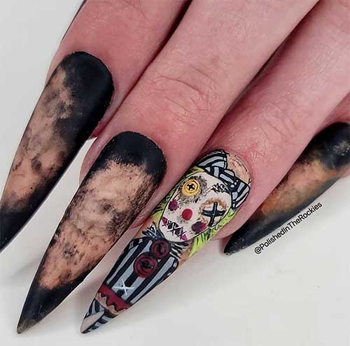 Long stiletto creepy Halloween doll nail design features matte smudged black nails with a creepy doll on an accent nail