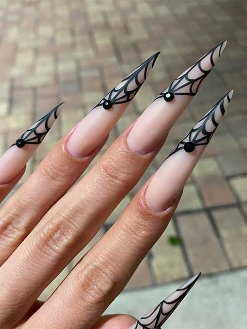 Long stiletto matte black diagonal French cobweb nails with a jet black rhinestone on each nail