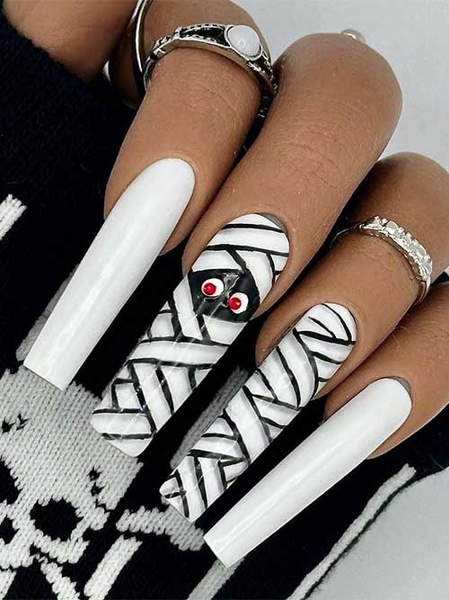 Long white Halloween nails with black and white mummy wrap nail art on two accent nails