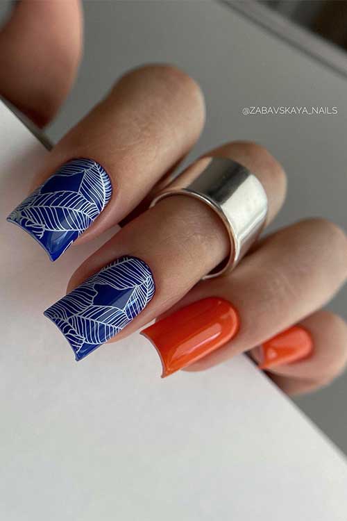 Medium square shaped Burnt Orange and Navy Blue Accent Nails Adorned with Hand-Painted White Leaves