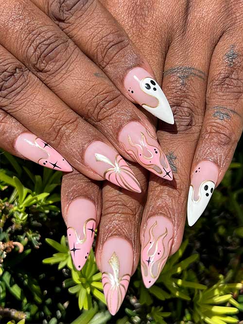 Nude pink Halloween nails with a pink pumpkin, celestial nail art, flame nail art, and a white ghost on each nail tip