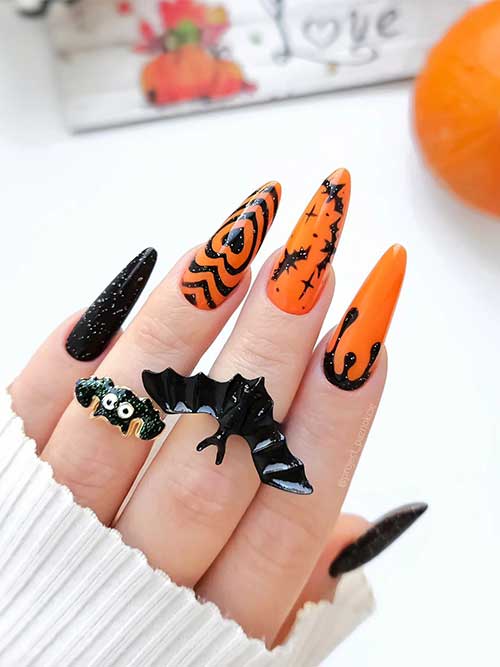 Black and orange Halloween nails with a little glitter and the design features black hearts, bats, and drip nail art