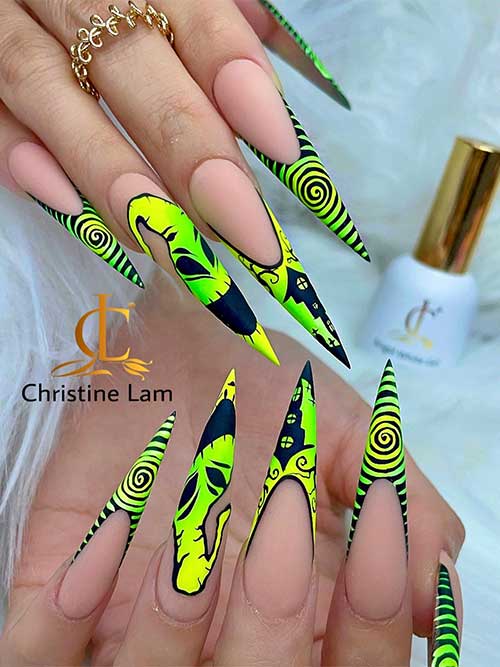 Long stiletto French tip oogie boogie man nails with green swirls over black tips.