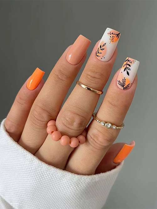 Autumn leaf nail art design features two vibrant orange nails, and two accent white milky nails with abstract nail art