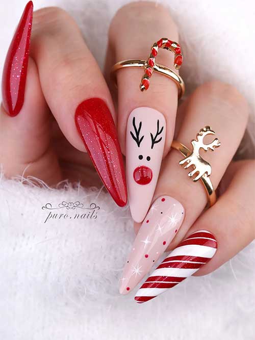 Long nude pink and red Christmas nails feature two glitter red nails and a matte nude pink nail with a reindeer shape