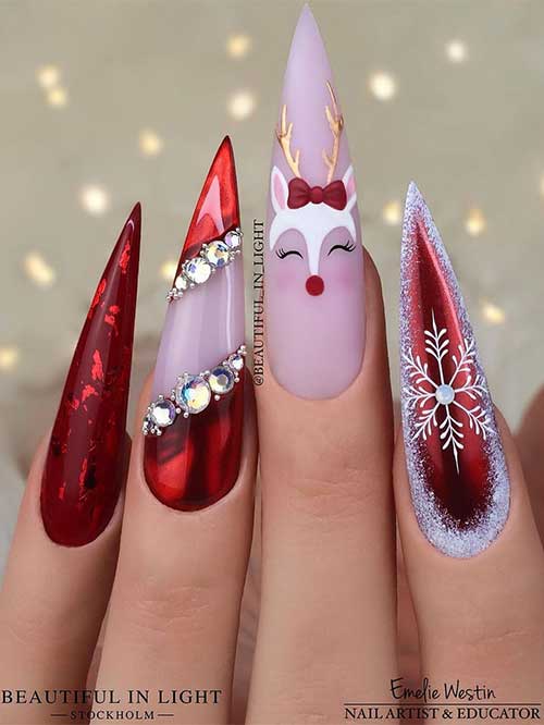 Long stiletto gel red Christmas nails feature a white snowflake, silver rhinestones, and a creative reindeer face on accents