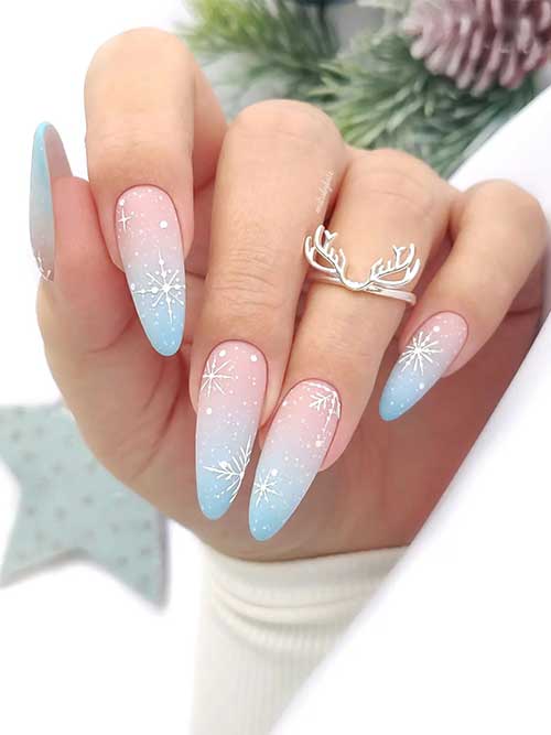 Long almond-shaped matte pastel blue and pink ombre winter nails adorned with big white snowflakes and white dots