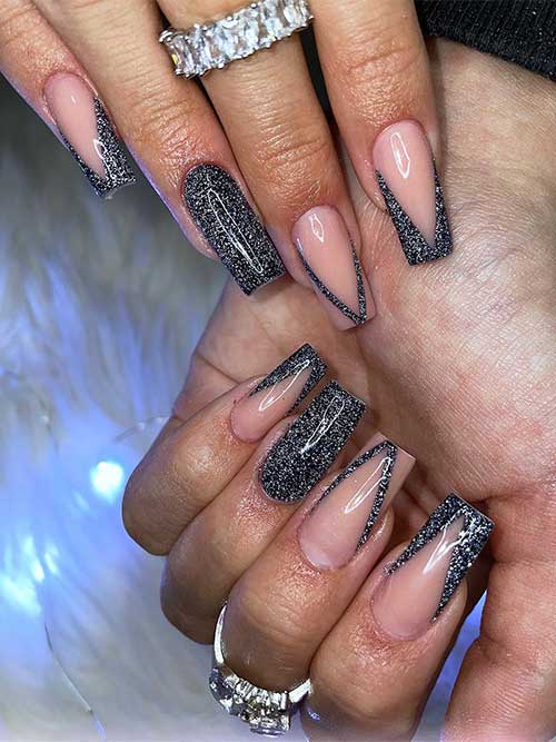 New Year’s nails feature nude base nails with V-shaped silver glitter black French tips with solid silver glitter black nail