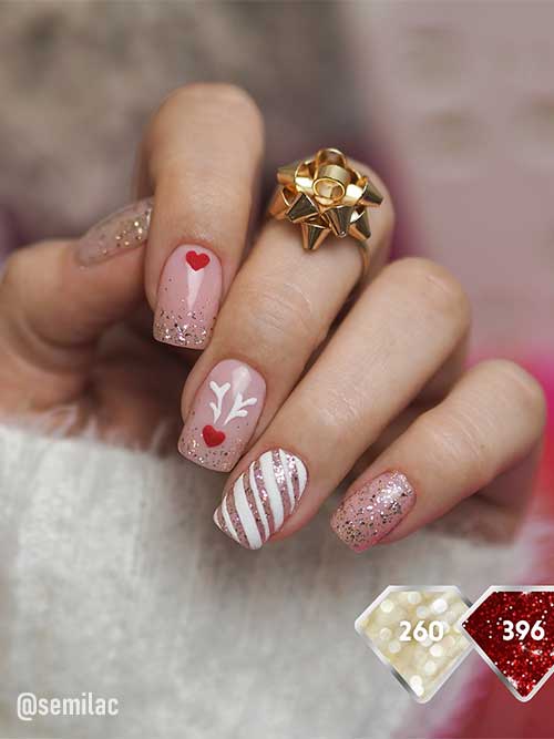 Short nude festive Christmas nails with a touch of gold glitter, red heart nail art, reindeer horns, and a candy cane accent