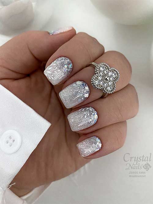 Short silver glitter nails with white snowflakes and holographic flakes are one of the best New Year's nail designs