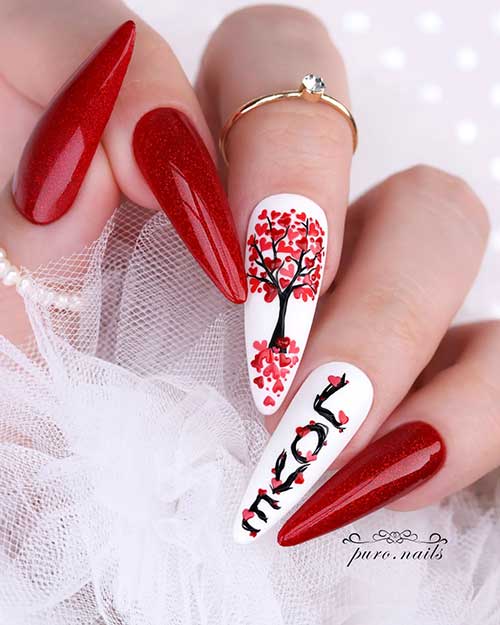 Cute glitter red Valentine’s Day nails with two accent white nails adorned with the “LOVE” word and red hearts as leaves
