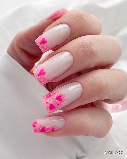Glitter French pink Valentine's Day nails over a milky white base color and adorned with hot pink heart shapes on the tips