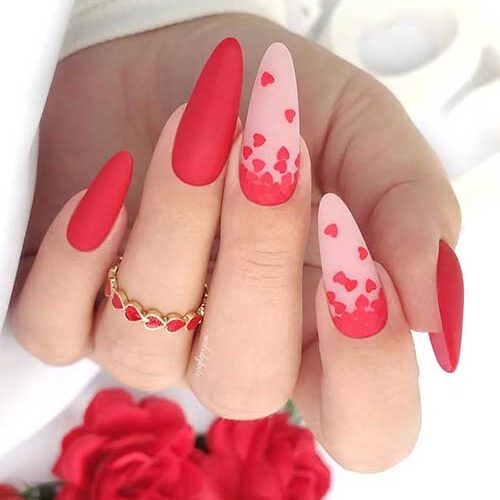 Gorgeous matte red Valentine’s nails with two accent nude pink nails adorned with red fallen heart nail art.